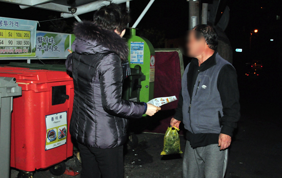 제주시청 공무원이 음식물쓰레기를 잘못 버리는 시민들을 계도하고 있다.