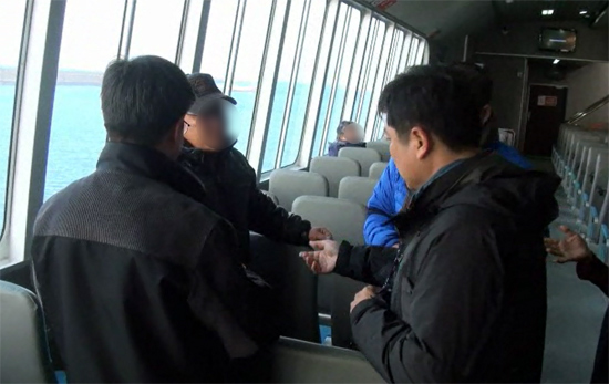 다른 사람의 신분증을 이용해 제주를 빠져나가려던 무사증 중국인 손모씨가 제주해경에 붙잡혔다. 제주해경이 여객선에 오른 손씨에게 신분증을 제시할 것을 요구하고 있다. / 제주해양경찰서 제공