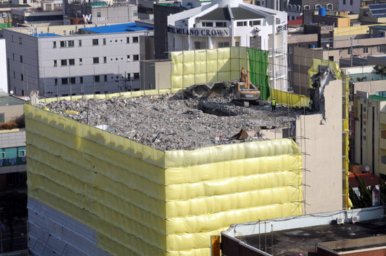 중장비가 옛 신한백화점 건물 위에 올라가 건물을 철거하고 있다.