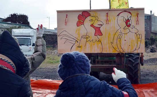 지역주민들이 닭이 그려진 패널에 계란을 던지고 있다.
